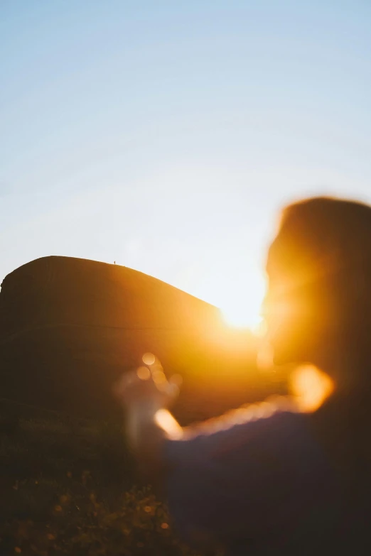 a person taking a picture of the sun, by Niko Henrichon, pexels contest winner, discreet lensflare, two suns, mountain, sunlight filtering through skin