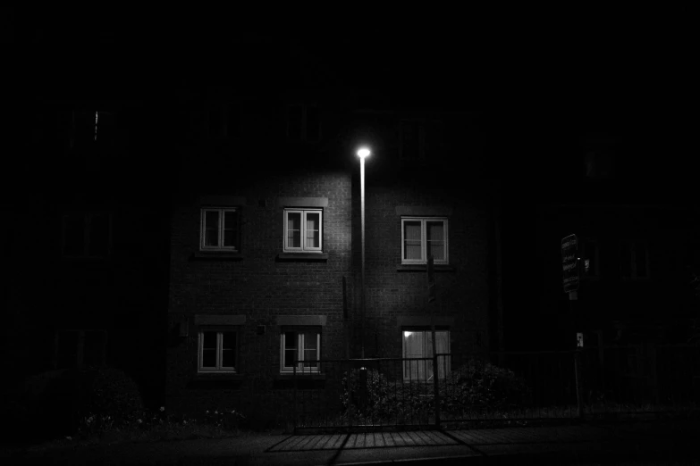 a black and white photo of a building at night, a black and white photo, unsplash, dark neighborhood, lonely!! stop light glowing, very realistic. low dark light, led