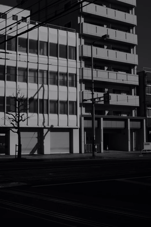 a black and white photo of a tall building, a black and white photo, unsplash, brutalism, vintage footage on tokyo streets, fully rendered light to shadow, storefront, in a suburb