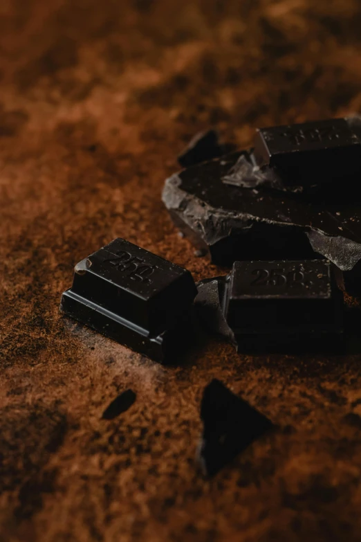 a couple of pieces of chocolate sitting on top of a table, pexels, panel of black, black goo, thumbnail, ready to eat