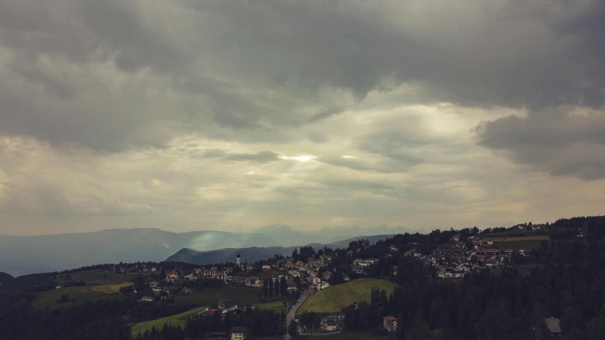 a view of a town from the top of a hill, by Sebastian Spreng, pexels contest winner, renaissance, ominous clouds, alpine climate, retro effect, early evening