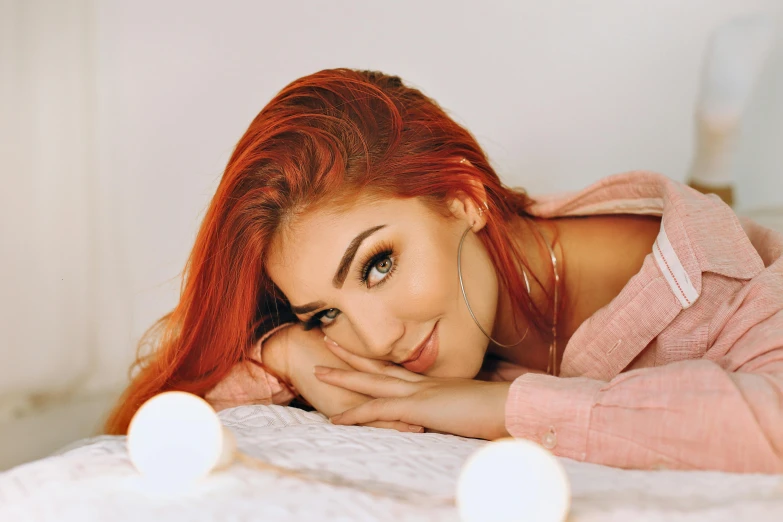 a beautiful young woman laying on top of a bed, trending on pexels, tachisme, red dyed hair, good lighted photo, sly smile, profile pic