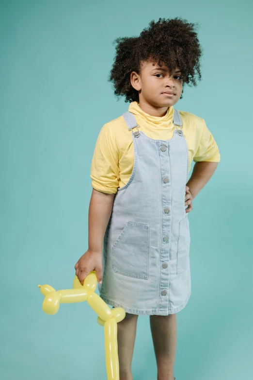 a little girl holding a yellow watering hose, inspired by Sarah Lucas, shutterstock contest winner, wearing a light blue shirt, studio photoshoot, portrait of vanessa morgan, toys