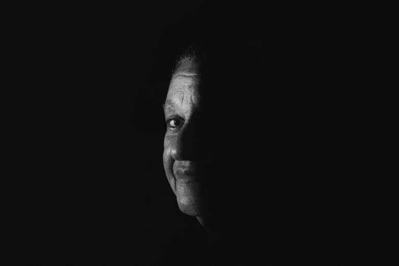 a black and white photo of a man in the dark, a black and white photo, unsplash, conceptual art, portrait 6 0 - year - old woman, without eyebrows, african american woman, her face is in shadow