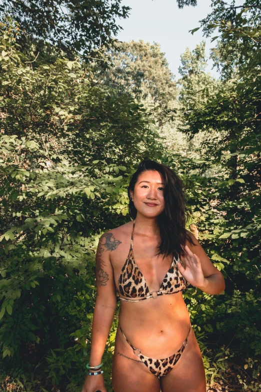 a woman in a leopard print bikini standing in the woods, inspired by Ren Hang, unsplash contest winner, wearing a low cut tanktop, portrait of christy ren, standing in front of a mountain, cottage hippie naturalist