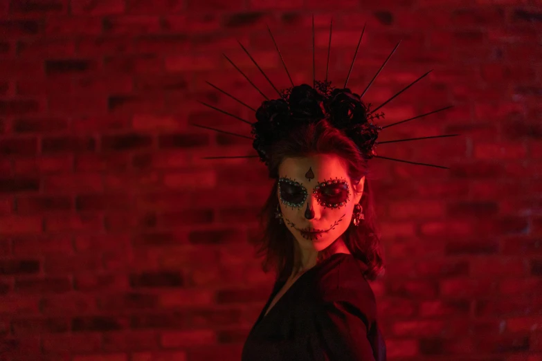 a woman standing in front of a brick wall, pexels contest winner, gothic art, (dia de los muertos), ram skull headpiece, red and cinematic lighting, animatronic angelina jolie