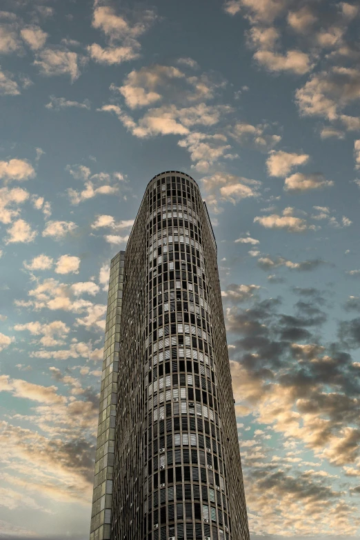 a very tall building with a lot of windows, inspired by Zha Shibiao, unsplash contest winner, spiral clouds, in barcelona, 8 k hi - res, late summer evening