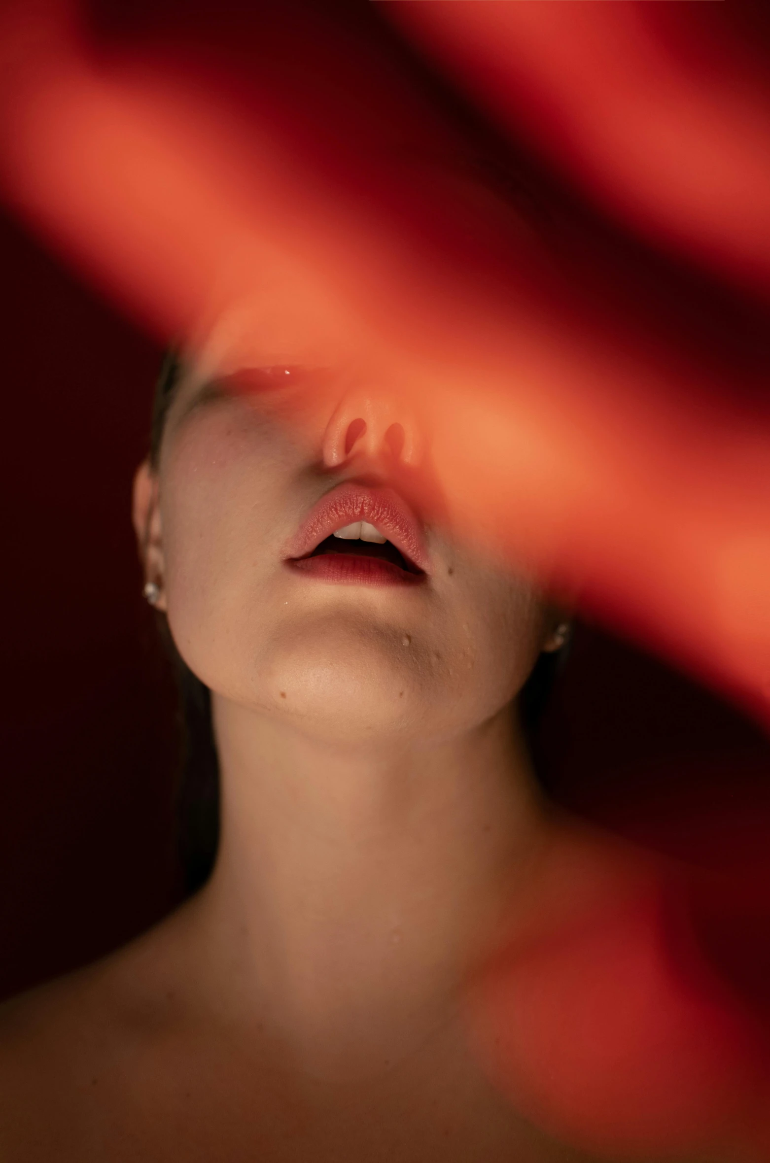 a woman standing in front of a red curtain, inspired by Elsa Bleda, pexels contest winner, neck zoomed in from lips down, lying on an abstract, portrait sophie mudd, glowing from inside