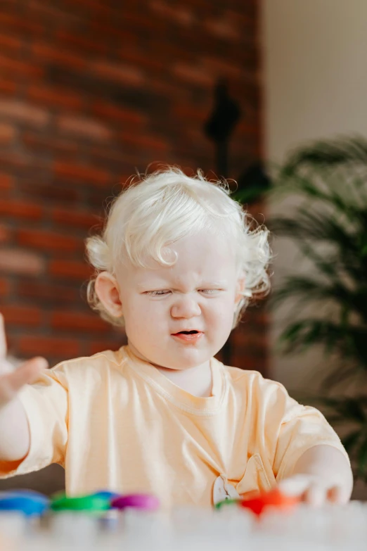 a toddler sitting at a table playing with toys, an album cover, pexels, incoherents, angry and pointing, albino hair, waving hands, kid a