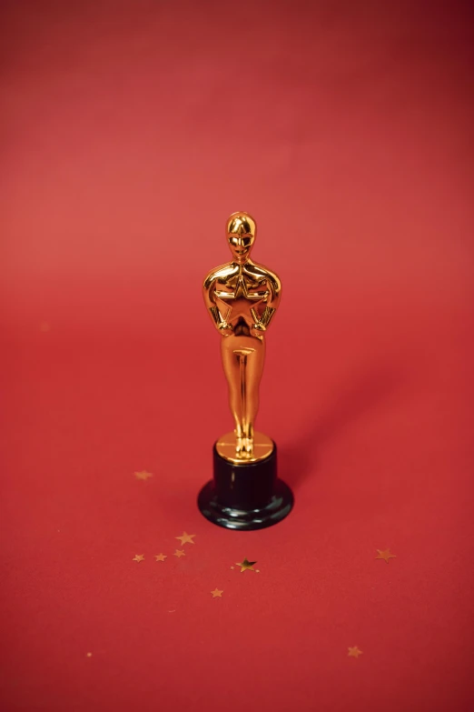 an oscar statue on a red surface, pexels contest winner, photorealism, gold flakes, porcelain holly herndon statue, ( ( theatrical ) ), video