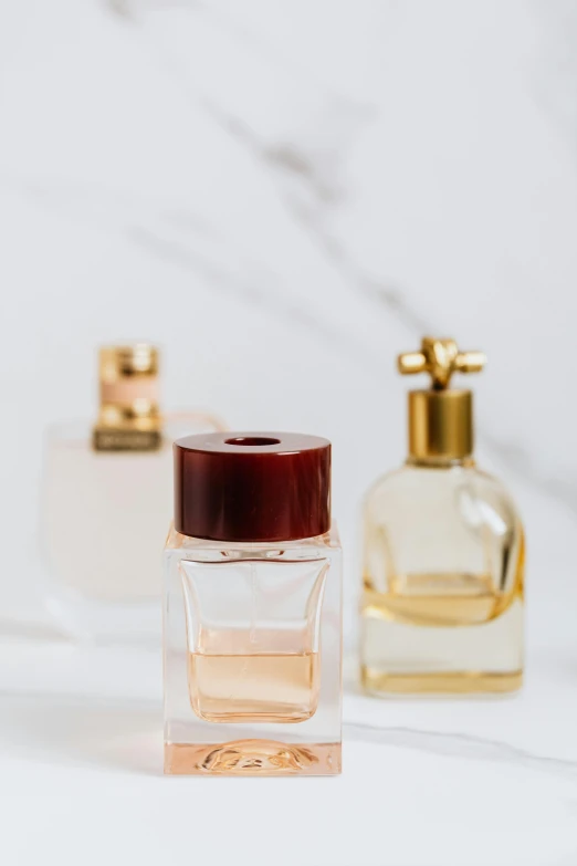 three bottles of perfume on a marble surface, trending on pexels, set against a white background, seductive lady, 1/30, small