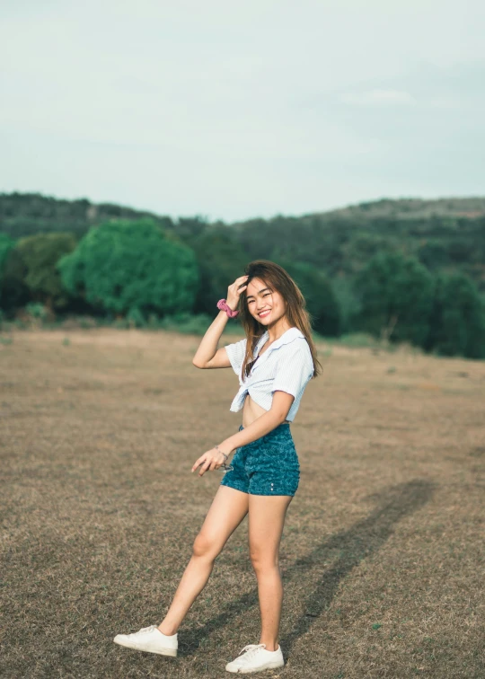 a woman standing in a field talking on a cell phone, a picture, pexels contest winner, croptop and shorts, satisfied pose, asian features, smol