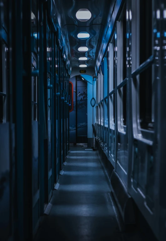 a long hallway with a clock on the wall, inspired by Elsa Bleda, pexels contest winner, inside an underwater train, behind bars, carriage full of computers, moody blue lighting