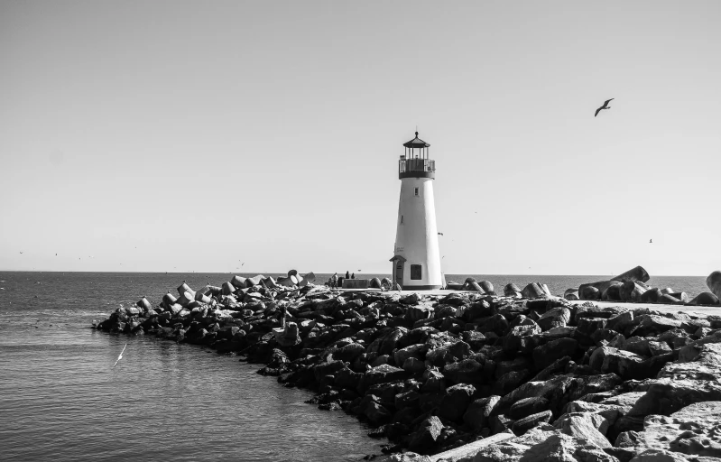 a black and white photo of a lighthouse, a black and white photo, pexels, the city of santa barbara, white stones, high quality upload, bright daylight