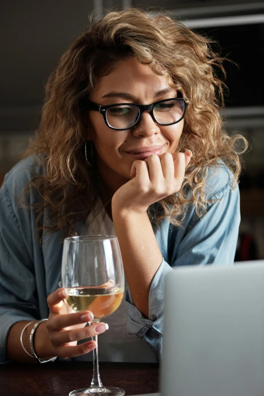 a woman sitting at a table with a glass of wine, in front of the internet, profile image, multiple stories, looking straight ahead