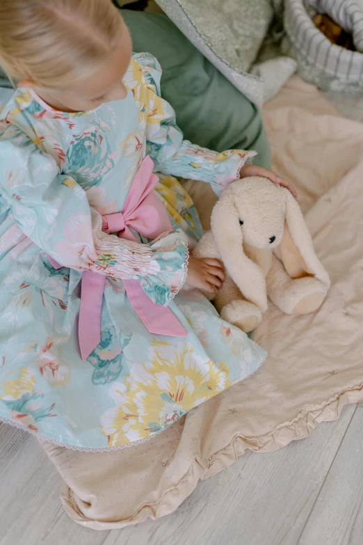a little girl sitting on a blanket with a stuffed animal, inspired by Annabel Kidston, rococo, lady with glowing flowers dress, turquoise pink and yellow, wearing a bunny suit, beautiful soft silky dress