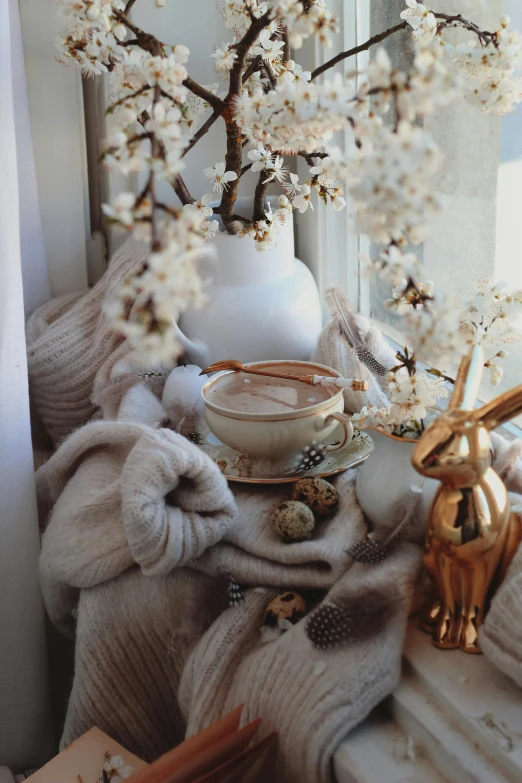 a white vase sitting on top of a window sill, a picture, by Zofia Stryjenska, trending on pexels, hot cocoa drink, bunny, golden accessories, blossoms