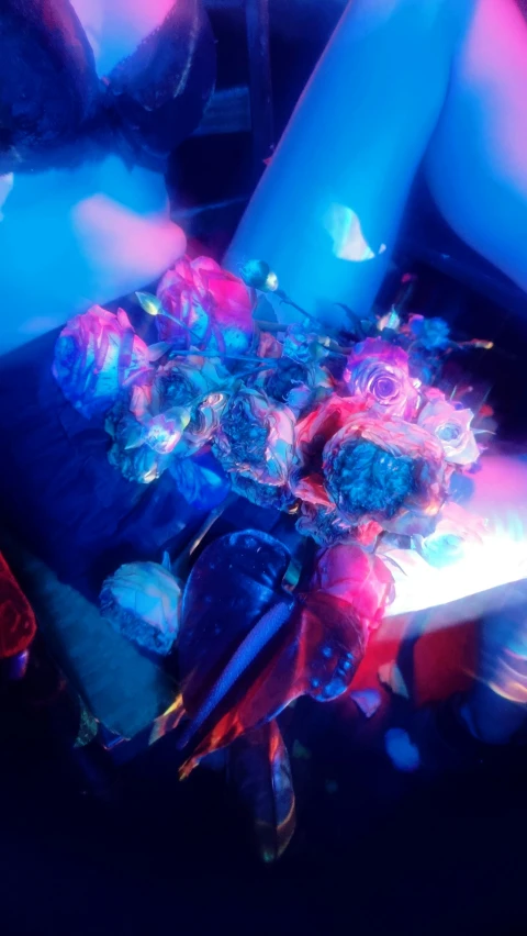 a woman sitting on a couch with a bouquet of flowers, an album cover, inspired by Bruce Munro, unsplash, blue and red lights, frayed edges. light leaks, opal statues adorned in jewels, cyberpunk cyborg. roses