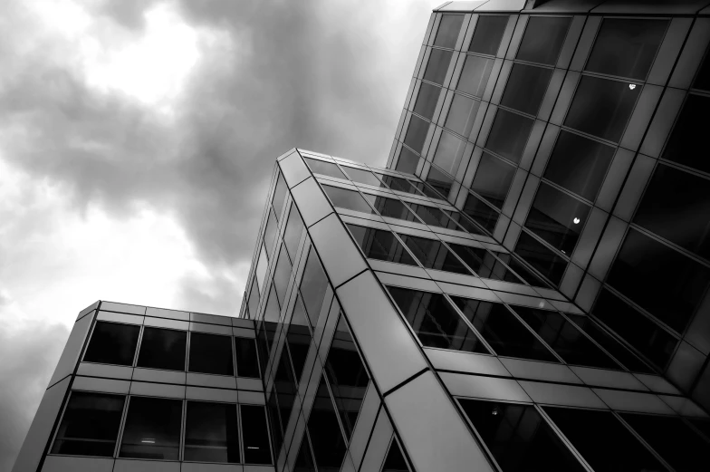 a black and white photo of some tall buildings, by Andor Basch, flickr, huge glass structure, grey cloudy skies, corners, high quality photo