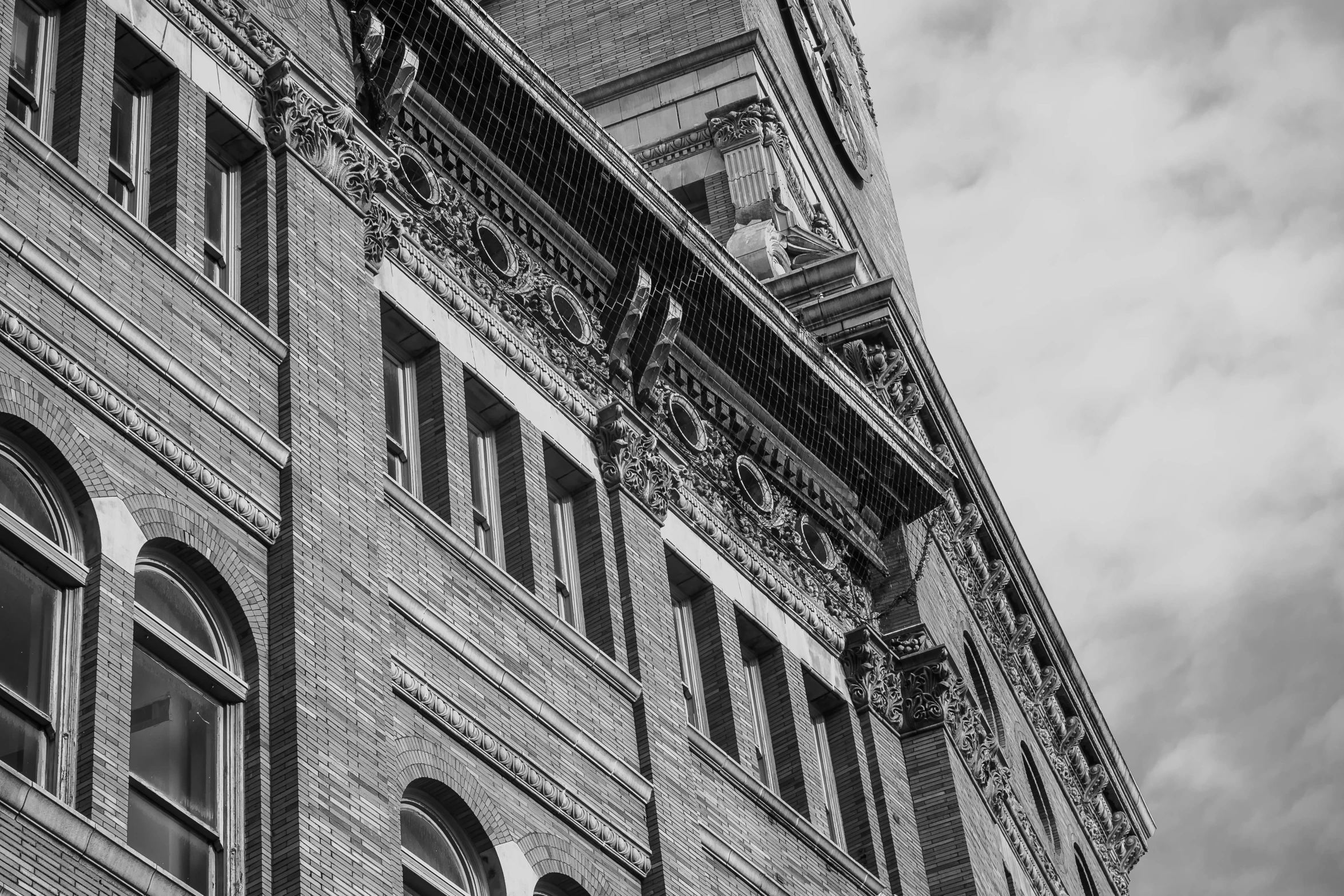 a clock that is on the side of a building, a black and white photo, by Sven Erixson, pexels contest winner, vancouver school, ornate architecture, brick building, high details photo, ascending form the sky