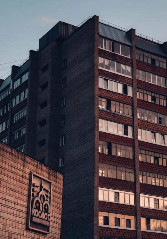 a tall brick building sitting in the middle of a city, inspired by Elsa Bleda, pexels contest winner, brutalism, hospital lighting, decorated with soviet motifs, фото девушка курит, late summer evening