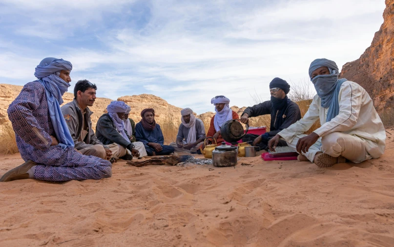 a group of men sitting on top of a sandy beach, les nabis, story telling, traditional clothes, 🤠 using a 🖥, braziers