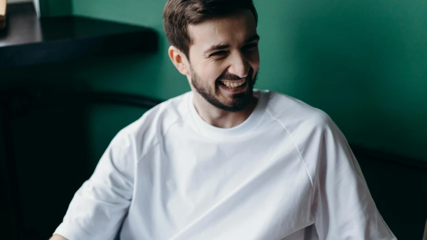 a man sitting at a table with a plate of food, earing a shirt laughing, hasbulla magomedov, avatar image, dressed in a white t shirt