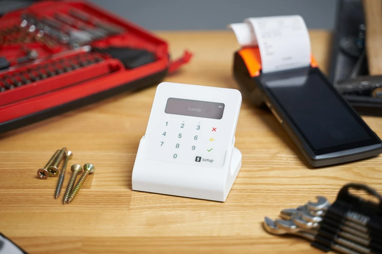 a cell phone sitting on top of a wooden table, cash register, white finish, multicoloured, full product shot