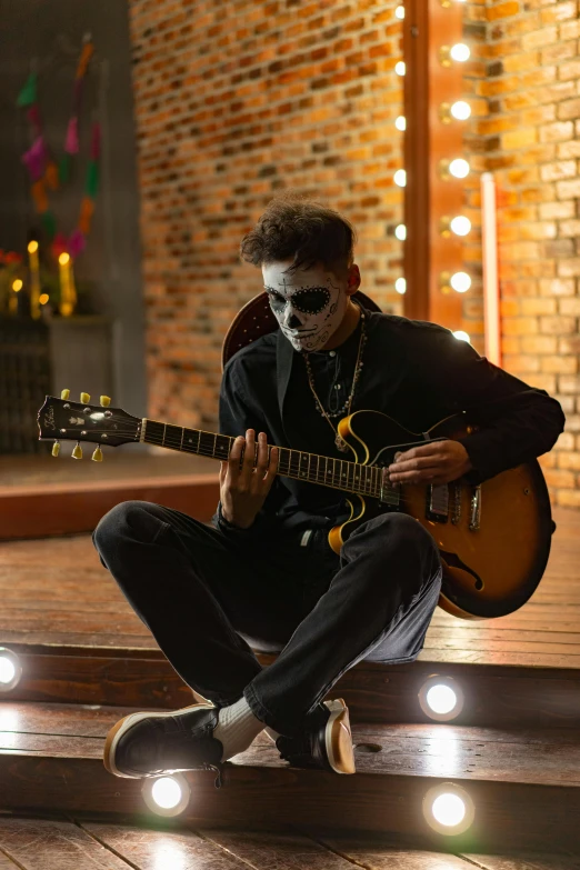 a man sitting on the steps playing a guitar, inspired by Michael Ray Charles, pexels contest winner, skull face paint, vantablack gi, on a stage, he wears an eyepatch