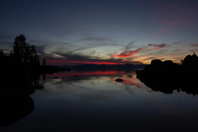 a large body of water with a sunset in the background, a picture, red lake, dark setting, camp, landscape photo