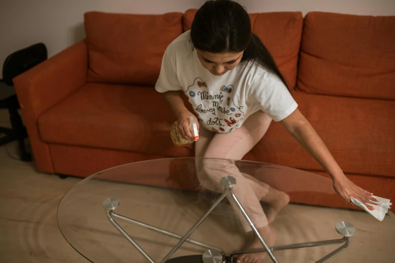 a woman is cleaning a glass coffee table, by Adam Marczyński, pexels contest winner, teenage girl, full body image, lit from bottom, lightweight