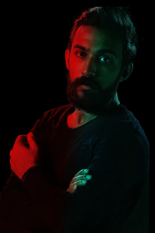 a man standing in the dark with his arms crossed, inspired by Camilo Egas, a portrait of rahul kohli, volumetric lighting. red, profile picture 1024px, scruffy man