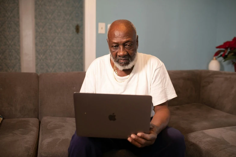 a man sitting on a couch using a laptop computer, by Dan Frazier, pexels contest winner, morgan freeman, virgil abloh, grandfatherly, ( ( theatrical ) )