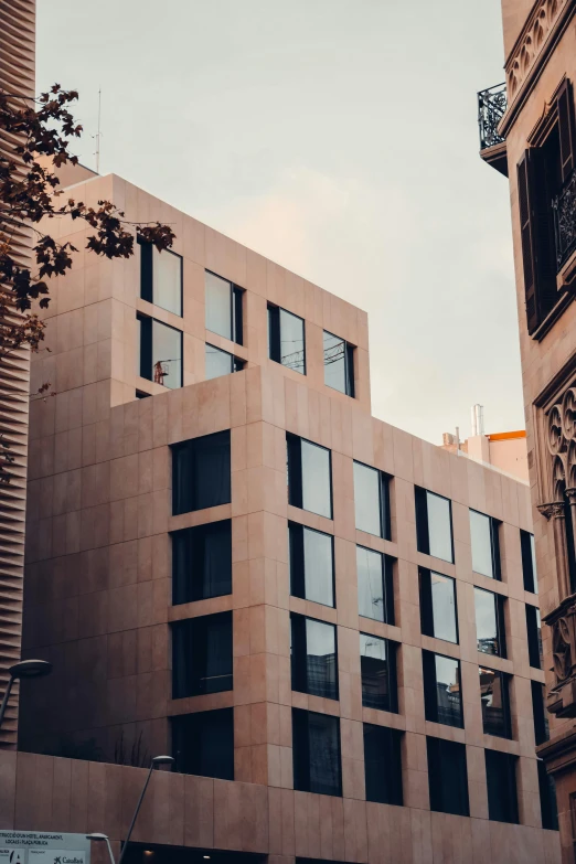 a tall building sitting in the middle of a city, inspired by Ricardo Bofill, pexels contest winner, modernism, gothic quarter, exterior view, sunfaded, thumbnail