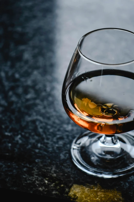 a glass of wine sitting on top of a table, inspired by William Grant Stevenson, unsplash, renaissance, glass with rum, black and brown, thumbnail, caramel