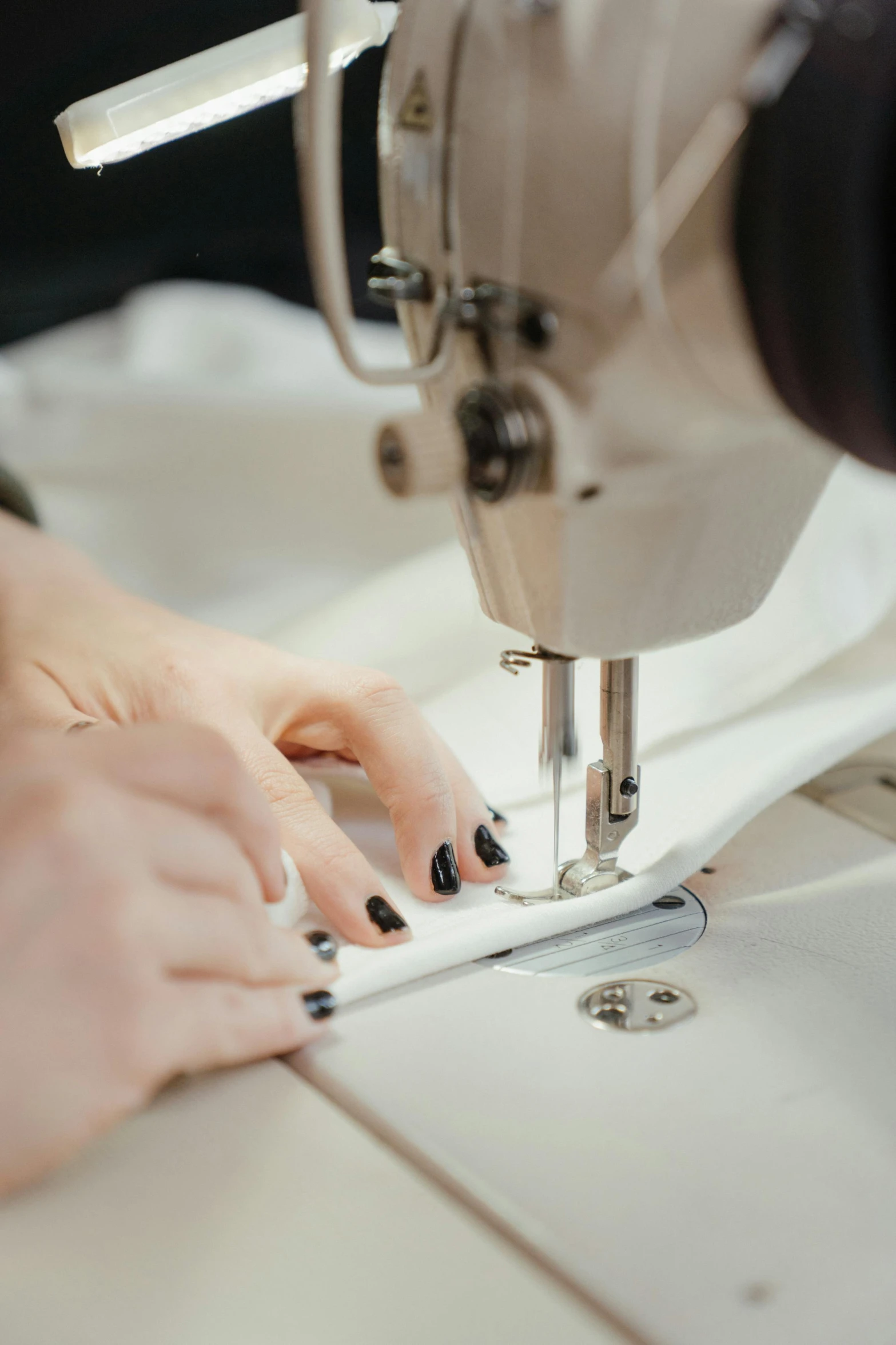 a close up of a person using a sewing machine, wearing white silk, leather clothing, construction, white