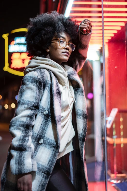 a woman standing in front of a store window, a portrait, trending on unsplash, flannel, nerdy black girl super hero, roots and hay coat, multiple lights