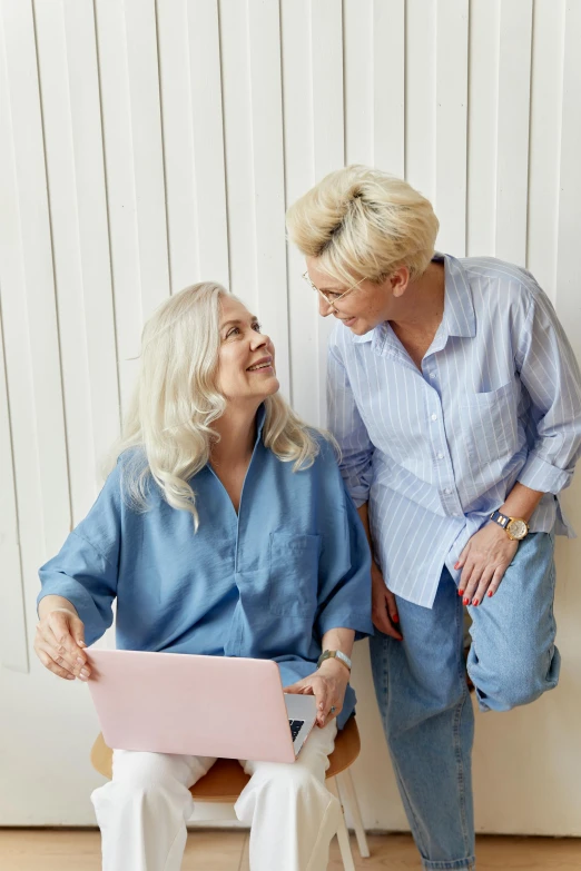 a couple of women sitting next to each other, wearing a light blue shirt, white-haired, computer, trending photo