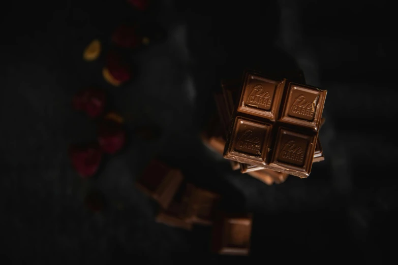 a piece of chocolate sitting on top of a table, pexels contest winner, it's dark, background image, stacked image, kramskoi 4 k