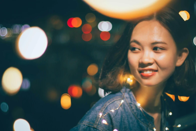 a close up of a person with lights in the background, pexels contest winner, young asian woman, half onesided smile, bokeh. rule of thirds, trending on imagestation