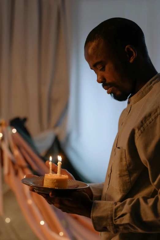 a man holding a plate with candles on it, black man, profile image, cake in hand, doing a prayer