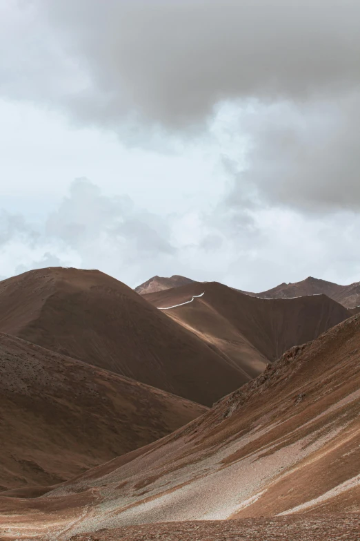 a man riding on the back of a horse down a dirt road, a matte painting, by Daniel Seghers, trending on unsplash, les nabis, looking down at a massive crater, brown colours, andes, slightly pixelated