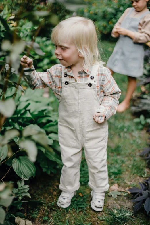 a little girl that is standing in the grass, an album cover, inspired by Elsa Beskow, pexels, wearing overalls, walking boy, foliage clothing, high resolution photo