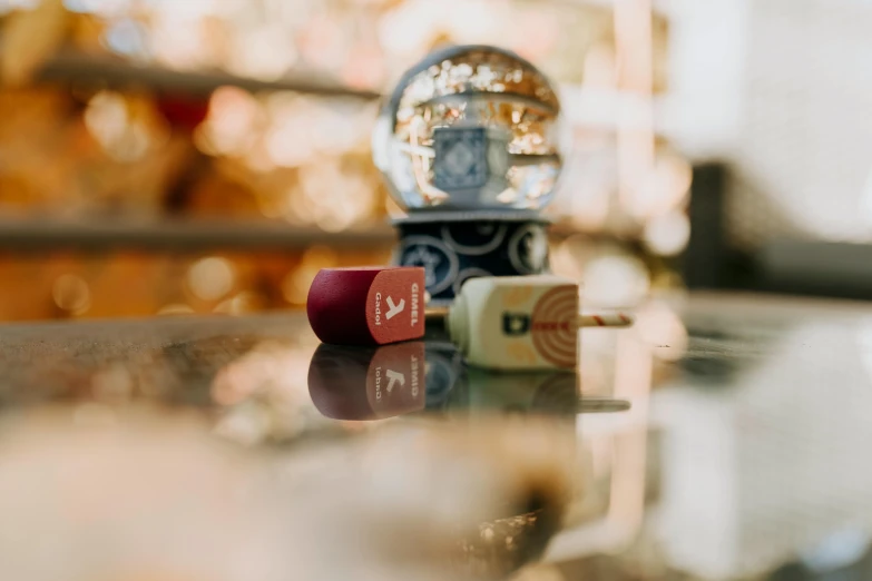 a snow globe sitting on top of a glass table, a picture, by Emma Andijewska, unsplash contest winner, cigarrette boxes at the table, solid coloured shapes, quirky shops, on a marble pedestal