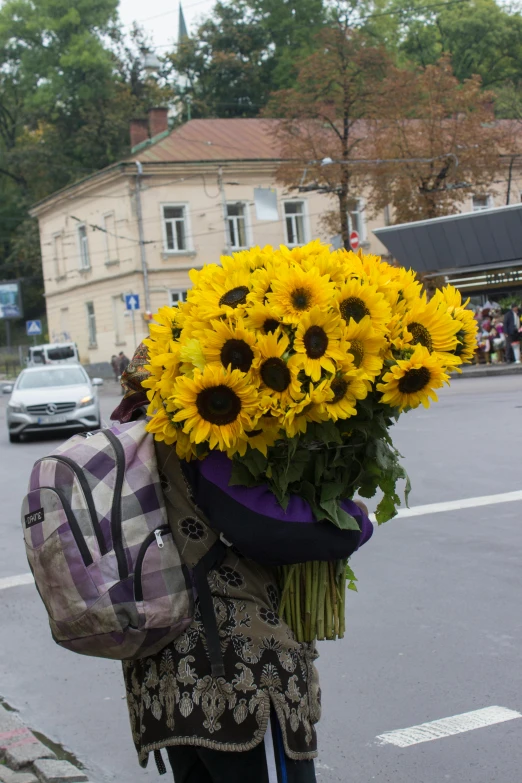 a woman walking down the street carrying a bunch of sunflowers, inspired by Mihály Munkácsy, hug, lviv, helmet instead of a head, shades of gold display naturally