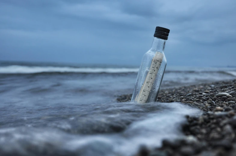 a message in a bottle on the beach, inspired by Storm Thorgerson, unsplash, minimalism, portrait, black, long
