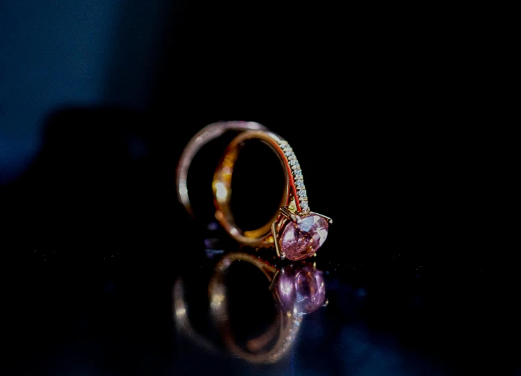 a close up of a ring on a table, pink and gold, shot on sony alpha dslr-a300, black jewerly, thumbnail