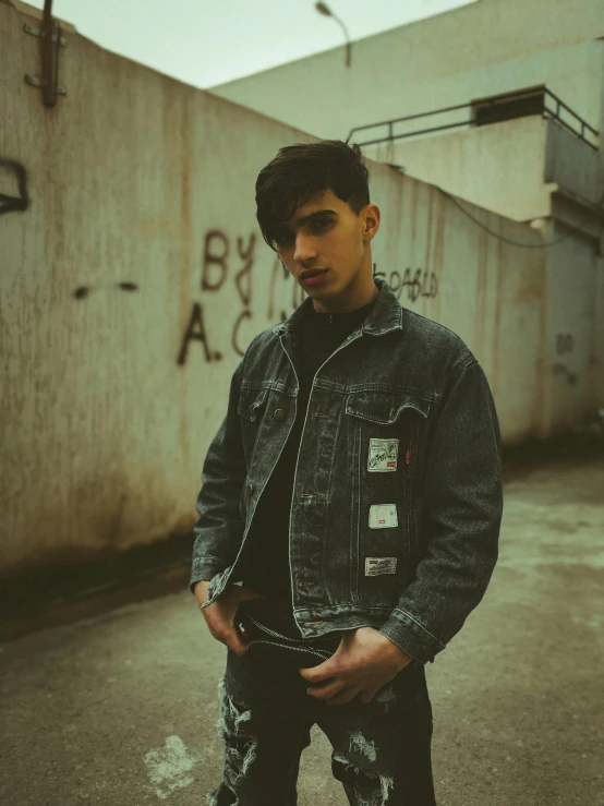 a man standing on a skateboard in a parking lot, an album cover, by Robbie Trevino, trending on pexels, jean jacket, non binary model, headshot profile picture, standing in a dark alleyway