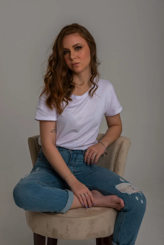 a beautiful young woman sitting on top of a chair, a portrait, inspired by Rhea Carmi, pexels contest winner, plain white tshirt, jeans and t shirt, meredit frampton style, headshot photograph