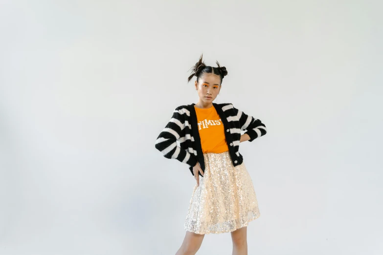 a young girl standing in front of a white wall, unsplash, kitsch movement, black and orange colour palette, young asian woman, striped sweater, white skirt and barechest